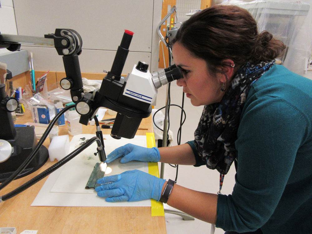 An intern examines a piece of copper through a microscope