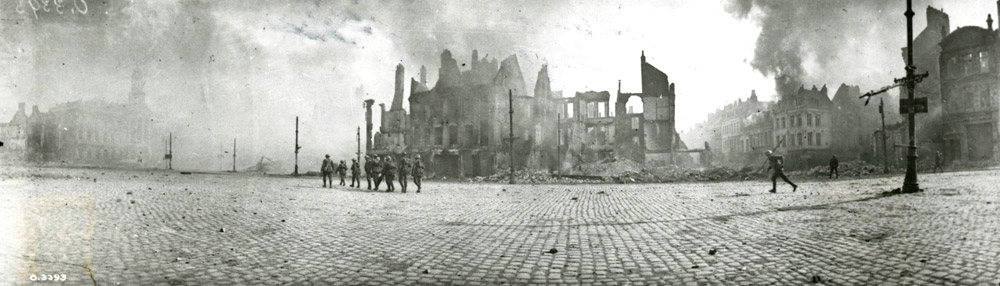 Black and white photo of soldiers crossing burned-out buildings
