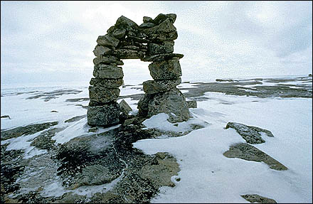 An Inukshuk on a snowy paysage.