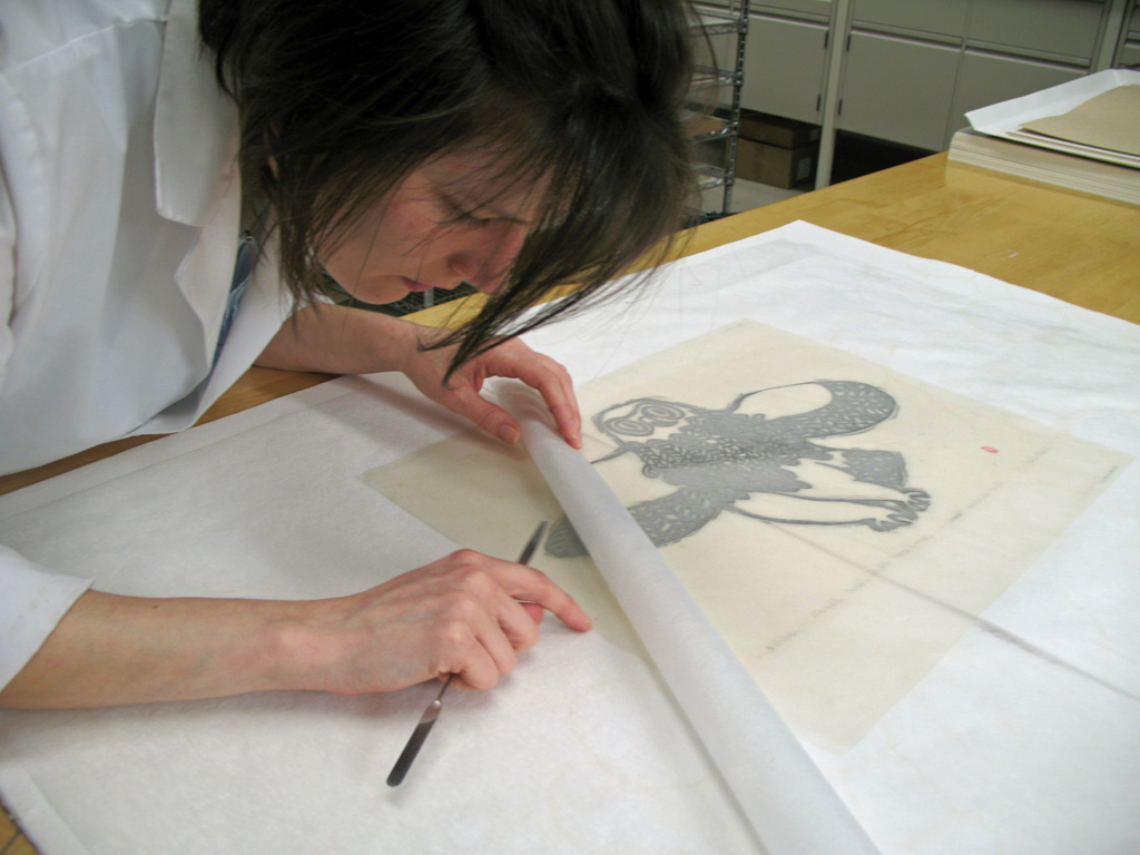 A woman with brown hair inspects a print