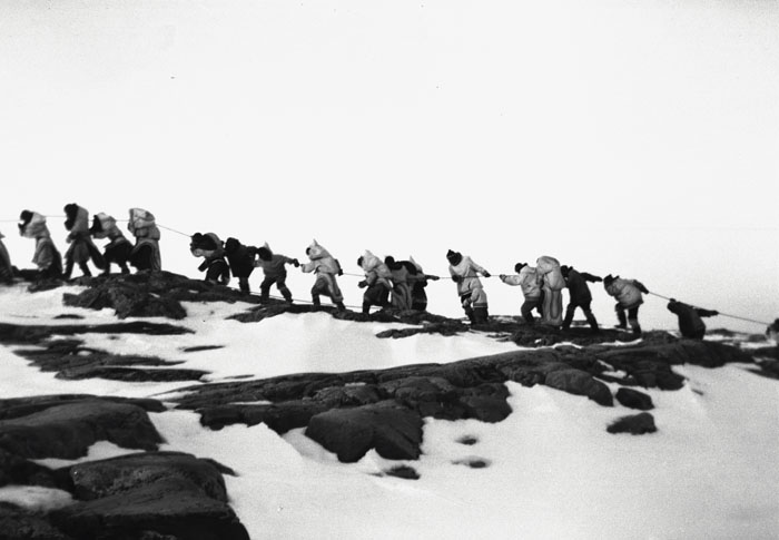 Inuit campers hauling a small boat at Keatuk camp, Baffin Island