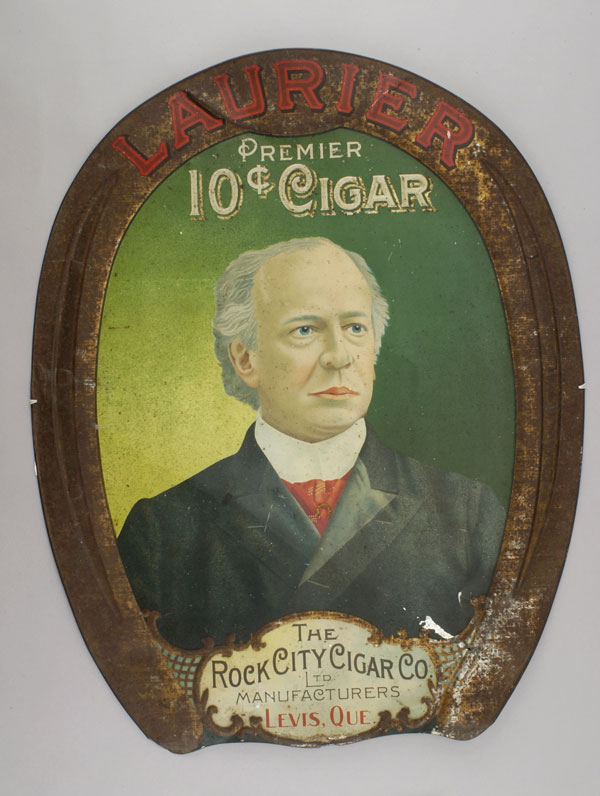 Tin advertising sign for The Rock City Cigar Co. The front of the sign shows Laurier on a green background. Canadian Museum of History, 1999.124.16