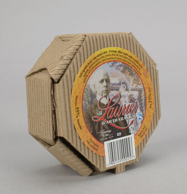 Cardboard packaging for Sir Laurier d'Arthabaska cheese. The label on the top of the box includes a portrait of Laurier and a view of the Laurier Museum in Victoriaville — Laurier’s former home — in the background. Canadian Museum of History, 2003.164.1