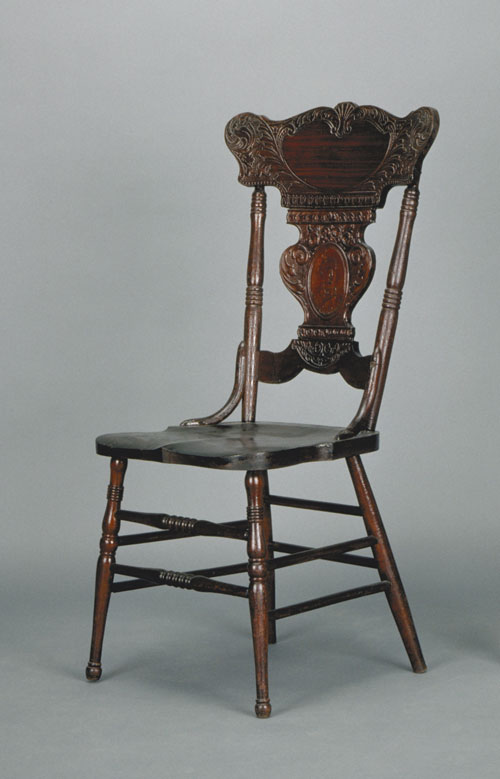 Press back side chair with ornate back featuring a cameo of Sir Wilfrid Laurier in the centre of the vertical back splat. Canadian Museum of History, A-1619 f