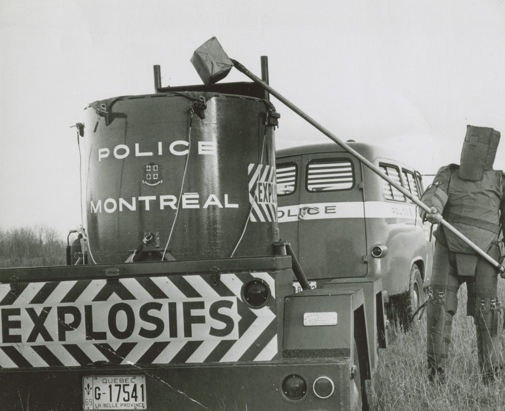 Sergeant Robert Côté, to the right of the bomb disposal trailer used by the Montréal police, 1968. Canadian Museum of History, Photo Archives, IMG2016-0278-0001-Dm, photographer unknown