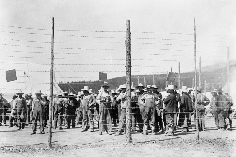 Image of internees behind fence at internment camp
