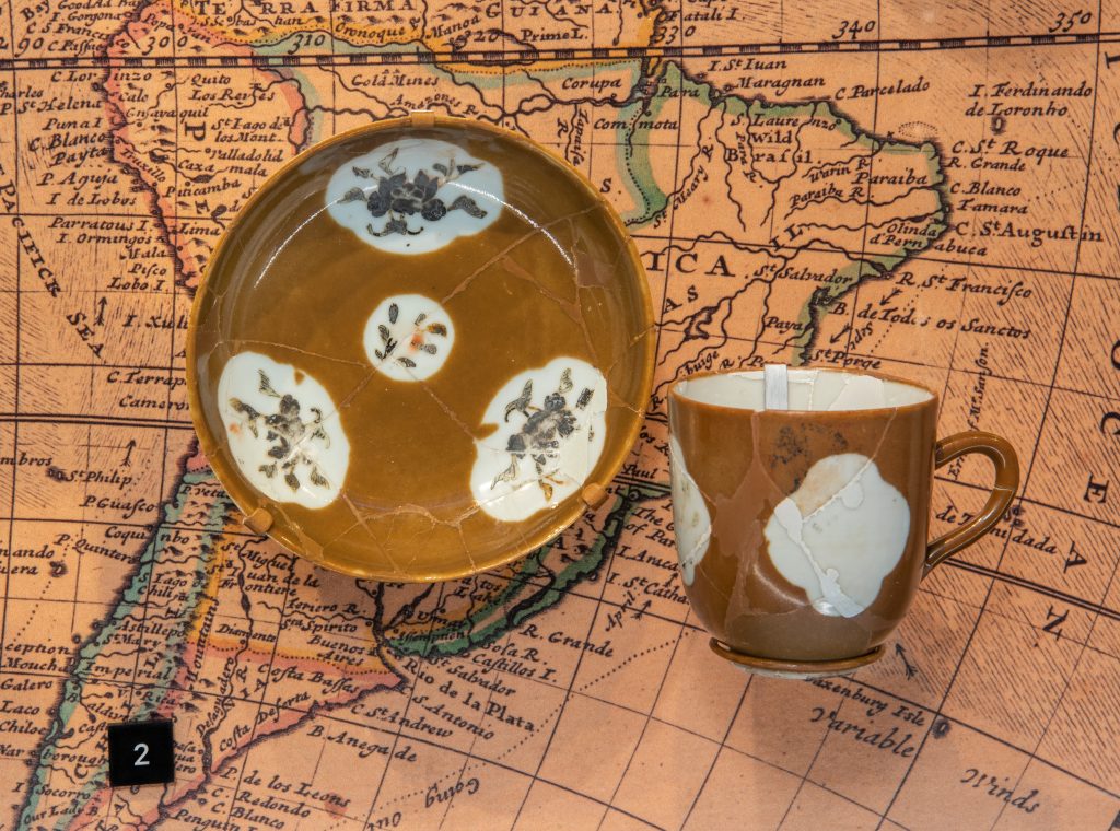 Chinese export porcelain cup and saucer in a style known as Batavian ware. The cartouches were originally decorated with enameled designs, which here have been damaged by the elements. Found on the site of the Machault, sunk in 1760.