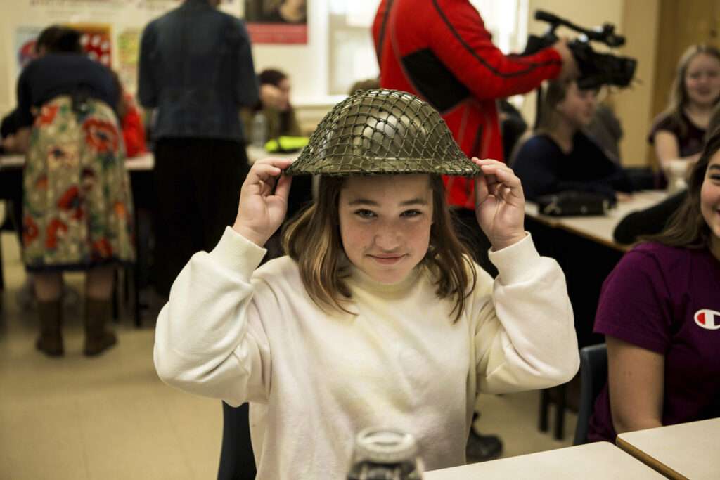 Student trying on helmet in classroom