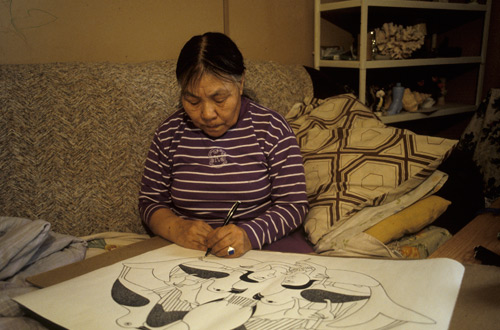 Kenojuak Ashevak using a black ink felt pen to draw what would become the print "Guardians of the Owl"