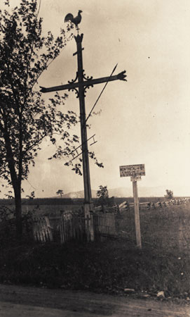 Croix de chemin ornementée d'un coq, d'une lance et d'une échelle sur la hampe. Sainte-Madeleine, Québec, 1923., © MCC/CMC, Edouard Zotique Massicotte, 60067