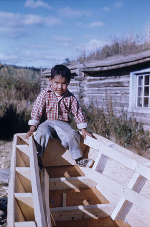 Steven Frost (Jr.), a Gwitch'in (Kutchin) boy sitting in a boat built by his father, Old Crow, Yukon, © CMC/MCC, Père J.M. Mouchet, S2004-1340