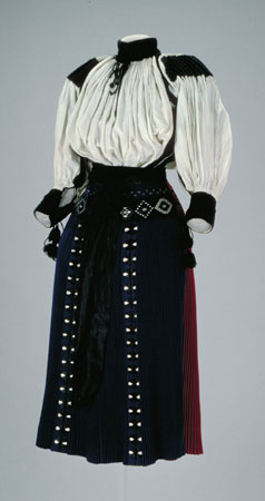 Apron made of blue wool, with narrow pleats. It is decorated and embroidered in black, white and green cotton., © CMC/MCC, 82-293.3