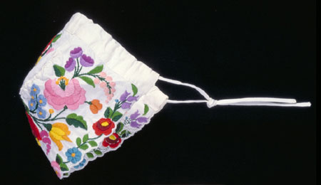 White cotton cap with a multi-coloured embroidered floral motif., © CMC/MCC, 76-514.6