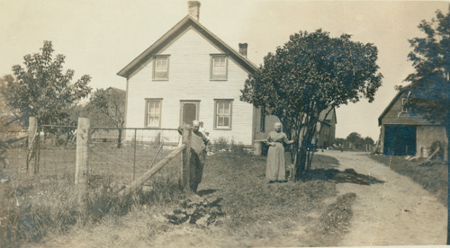 Photograph of Mr. and Mrs. Hawn, weavers, standing in front of their house in Newington, Ontario
