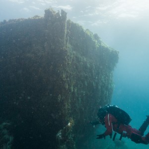 A diver is scuba diving near a shipwreck.