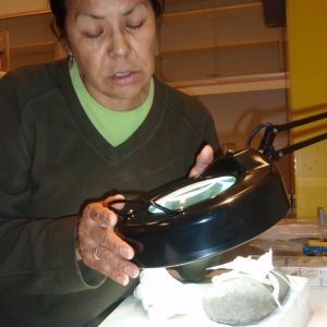 A woman examines at an artifact.