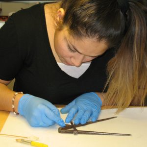 A woman examines a metal tool.