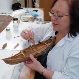 A woman examines a small boat.