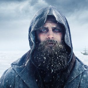 A bearded man in a hoodie standing in the snow.