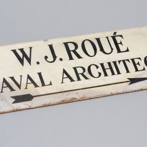White sign with black lettering that reads “ W. J. Roué Naval Architect.”