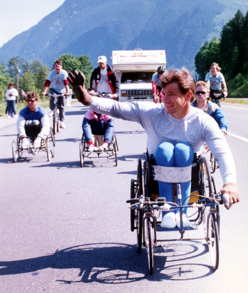 People in wheelchairs and on bicycles on the paved road