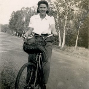 Woman on her bicycle in a white collared shirt and trousers