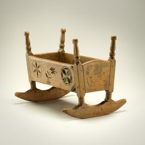 Miniature wooden cradle with carvings of flowers and birds