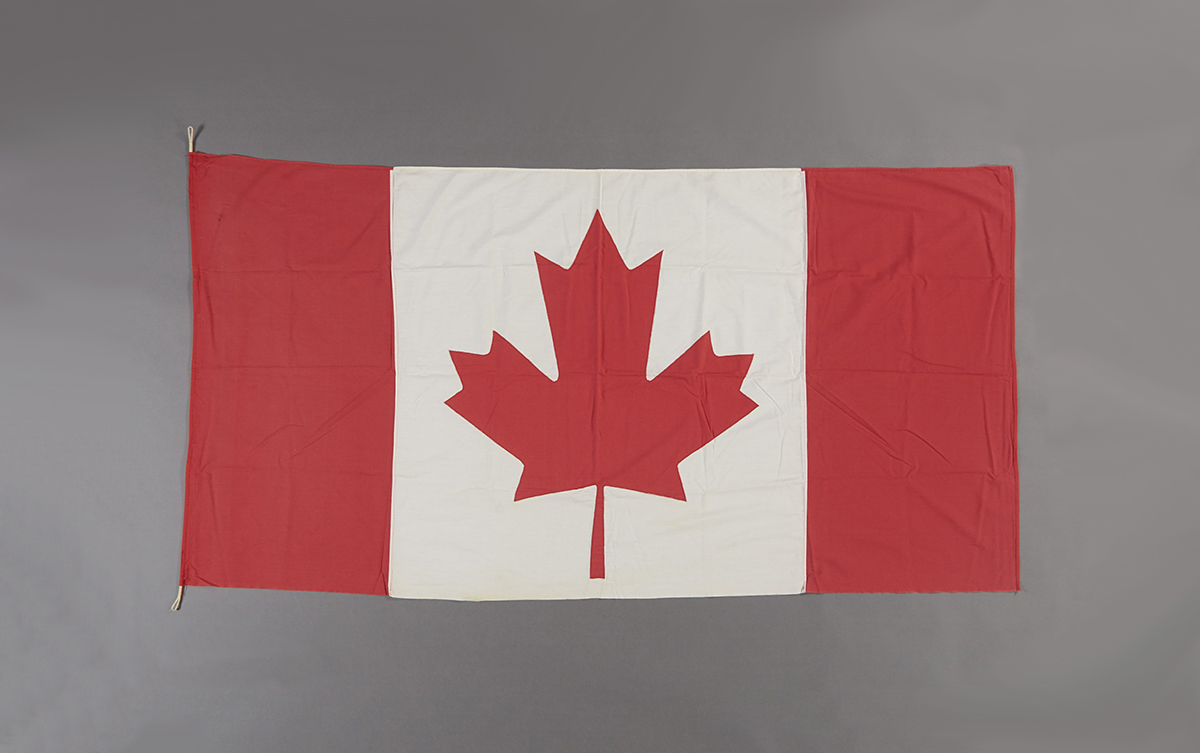 A Canadian flag hanging in Ottawa, against a grey background.