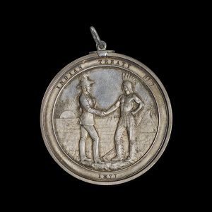 Silver medal featuring an Indigenous man shaking hands with a uniformed official