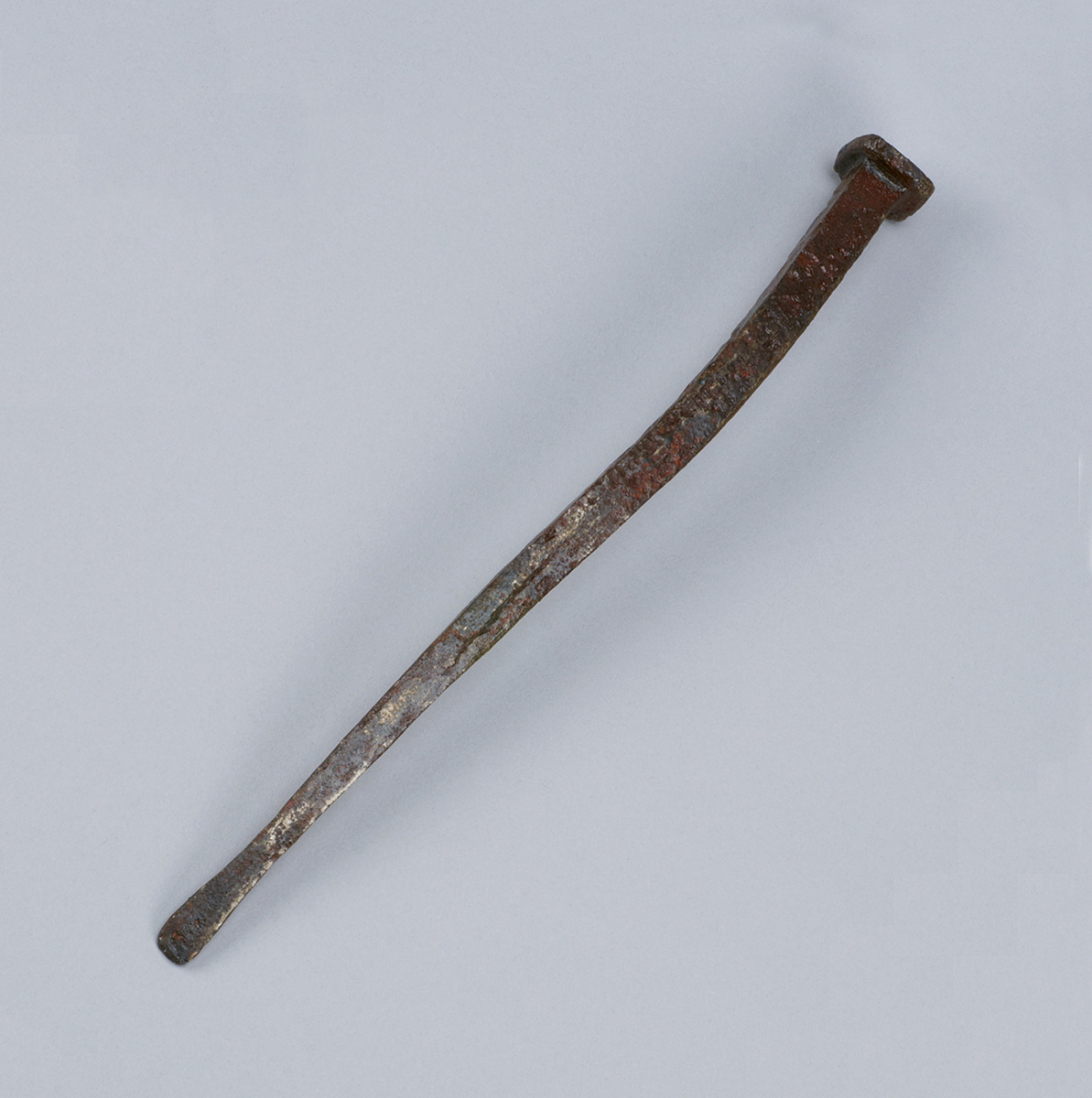 A rusty metal tool on a white surface in the Canadian Museum of History.