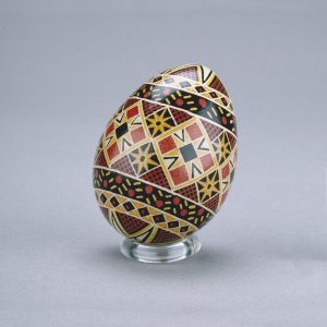 A Ukrainian Easter egg decorated with an intricate star-and-diamond pattern in black, red, brown and white.