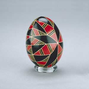 A Ukrainian Easter egg decorated with contrasting diamond shapes in red and black, separated by yellow lines.