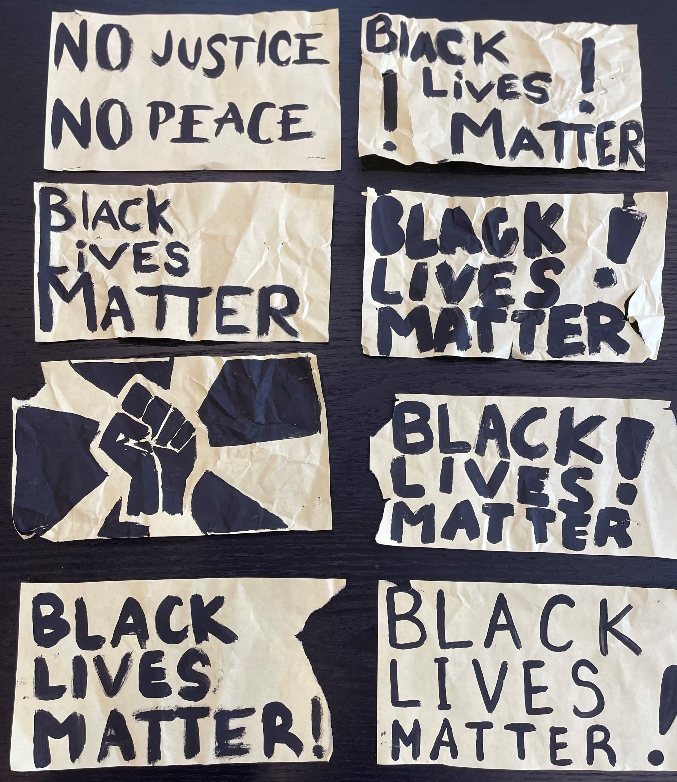 Eight small posters. One shows a raised fist, several say “Black Lives Matter!” and one reads “No Justice No Peace.”