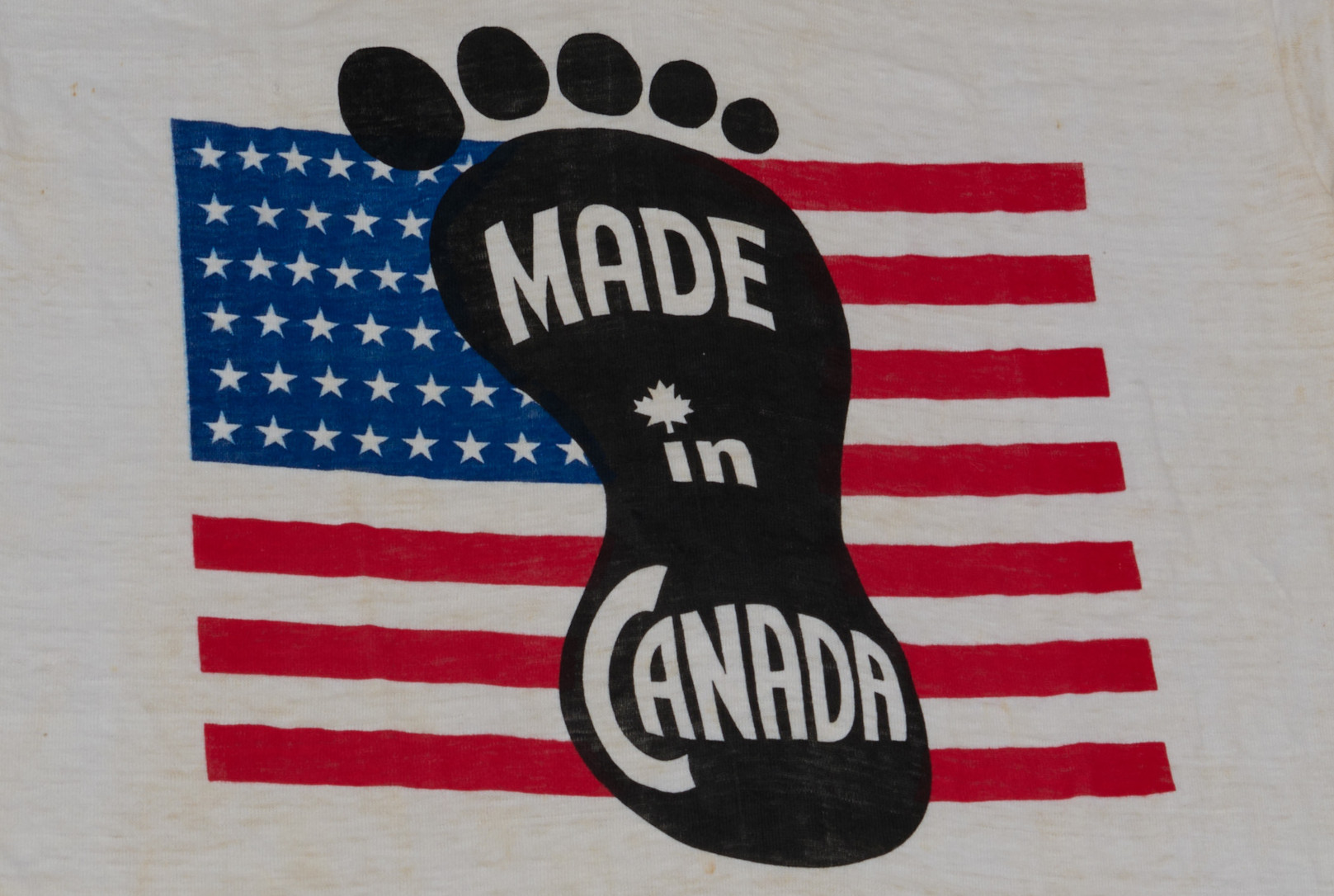 A red, white and blue U.S. flag, overlaid with a black footprint and white text that reads, “Made in Canada.”