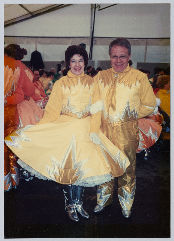 Two people wearing elaborately stitched costumes in yellow, gold and silver.