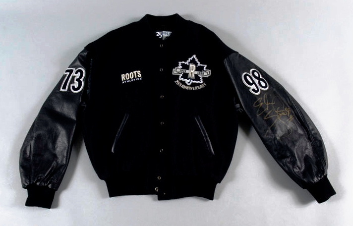 A black bomber-style jacket with a cloth body, leather arms, and black –and-white decorative patches.