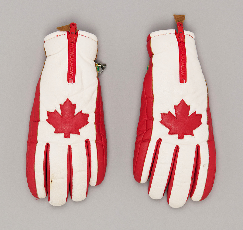 White leather ski gloves with red design details including a maple leaf on the back.