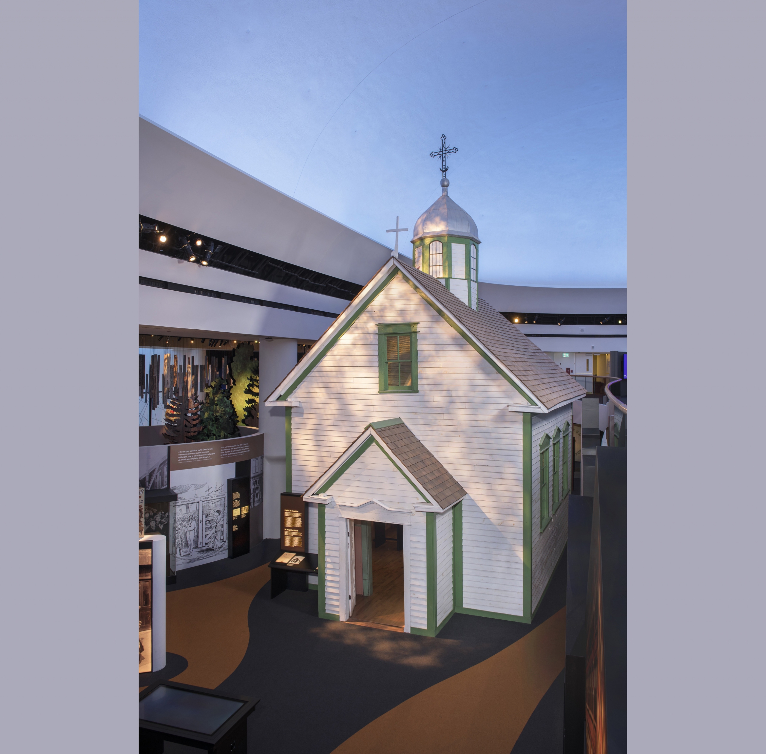 A small church with horizonal wooden slats painted white, and green strips around the windows, doors and edges.