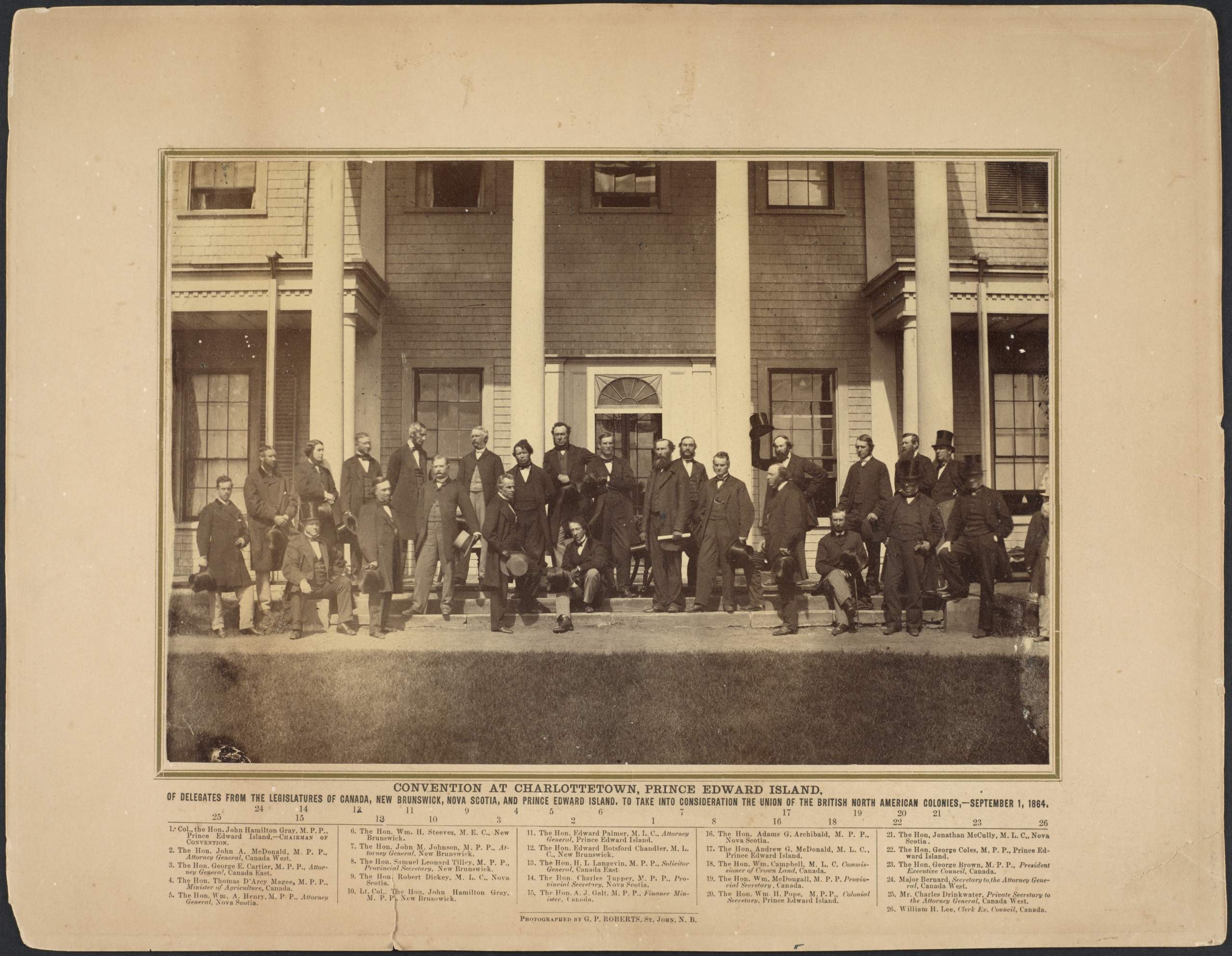 Black and white photo of men gathered in front of a building. 