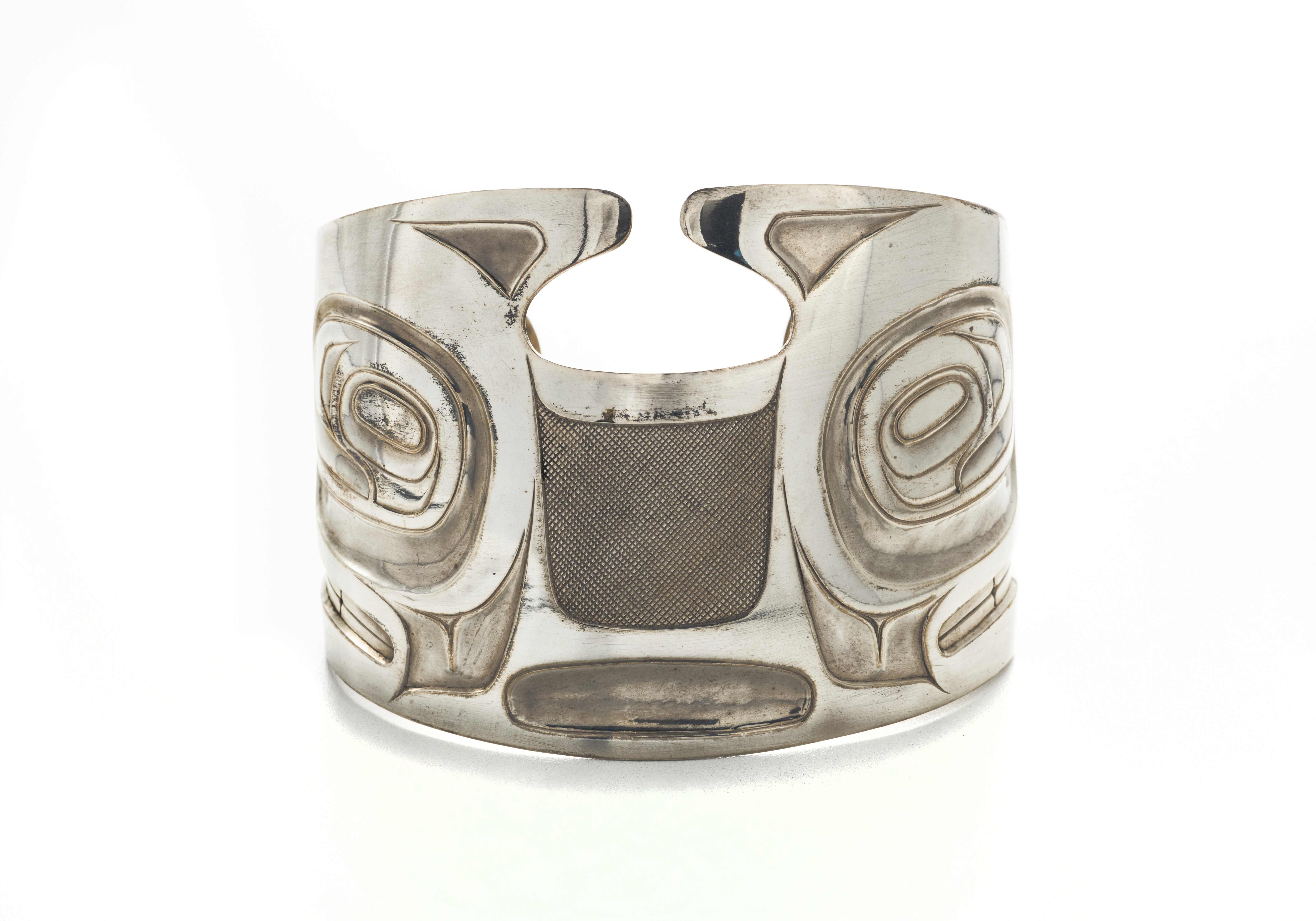 silver cuff bracelet with formline whale design carved on it