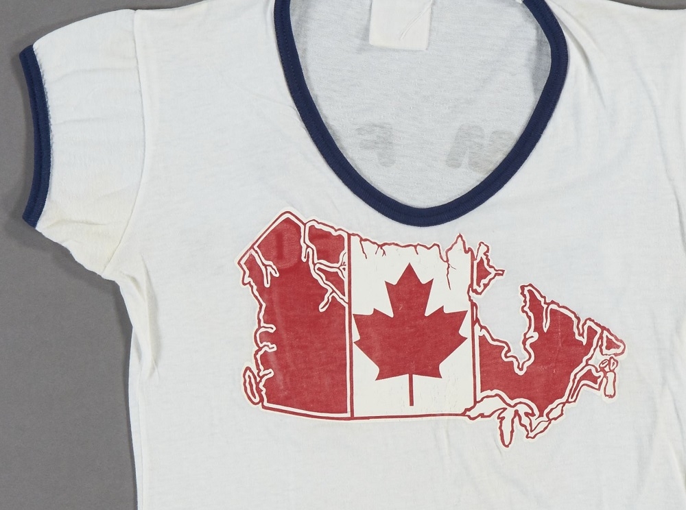 Teeshirt en coton blanc arborant le drapeau canadien superposé à la carte du Canada.//White cotton T-shirt with the Canadian flag in the shape of Canada