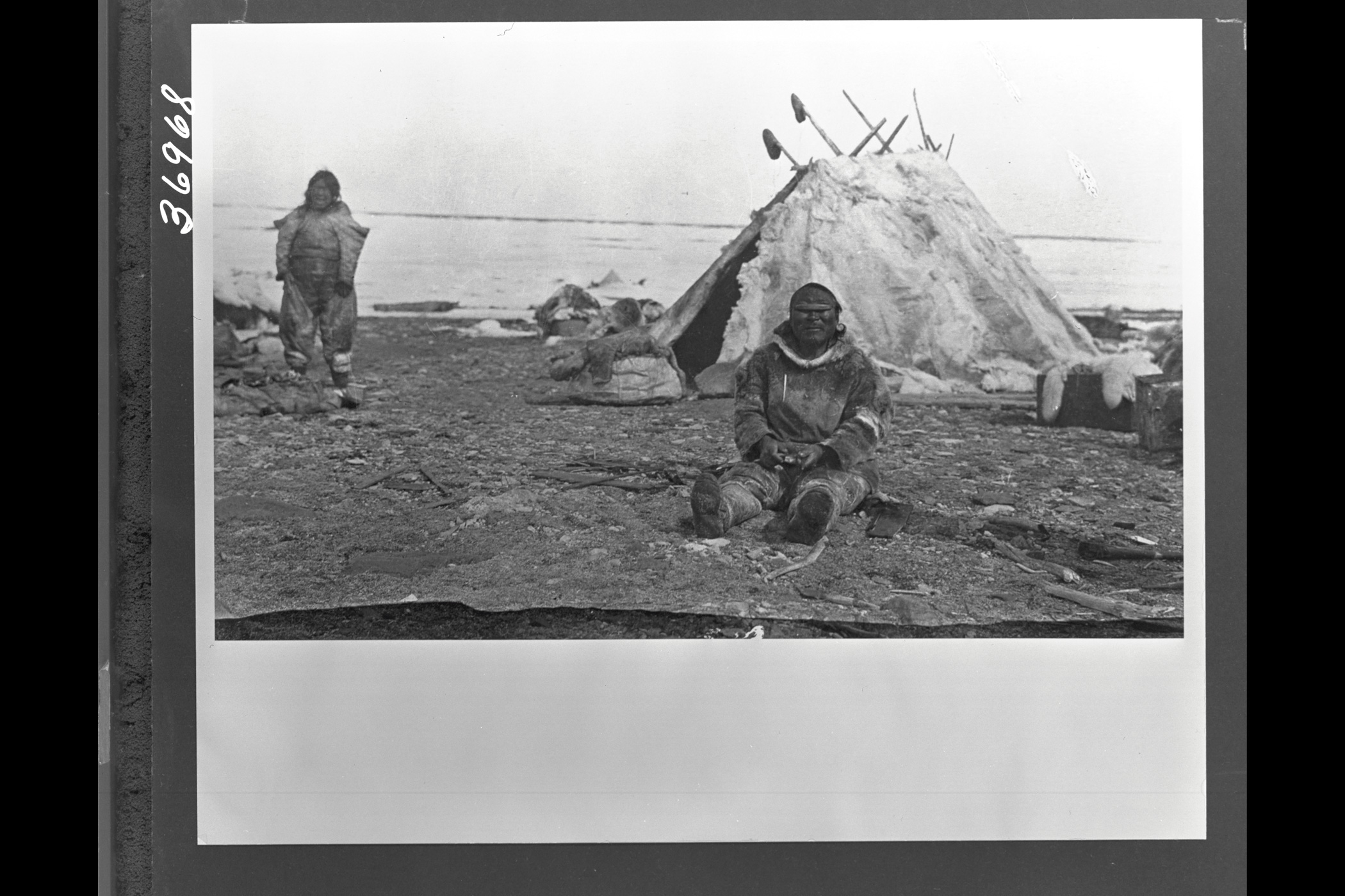 //Man wearing snow goggles carving wood in front of hide tent