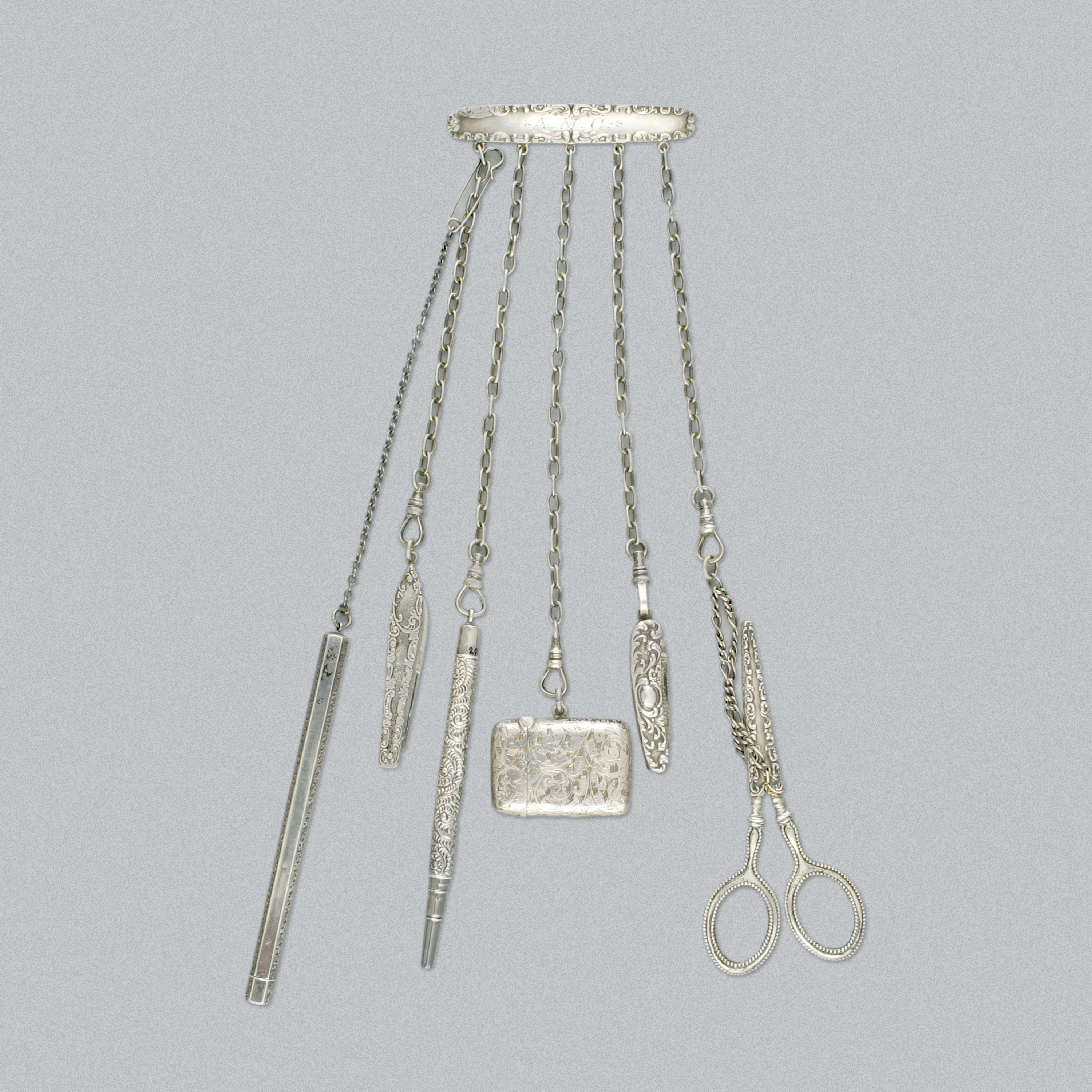 Châtelaine en argent sur fond gris. //Silver chatelaine on grey background