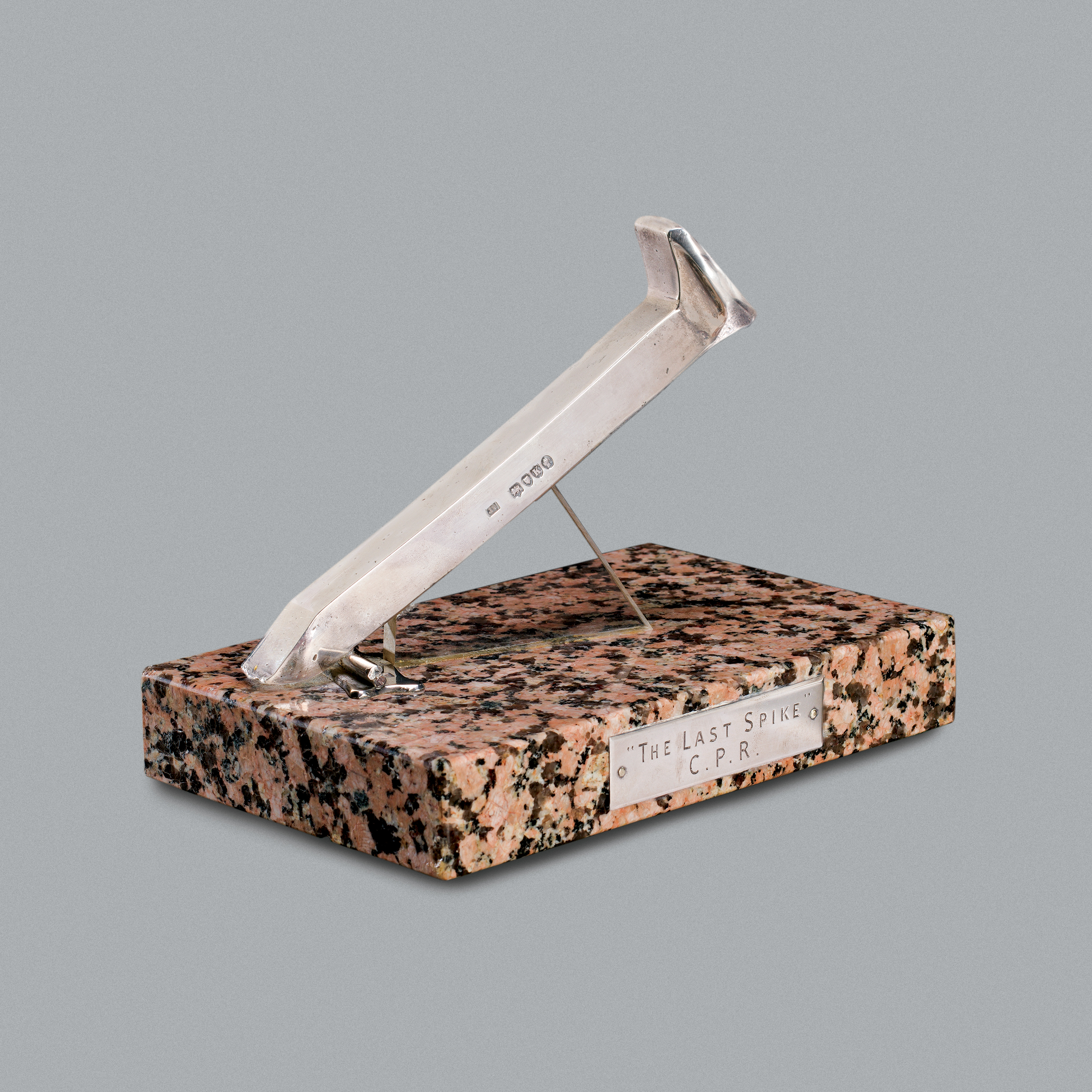 Reproduction d’un crampon de chemin de fer sur un socle en granite. //Reproduction of a railway spike on a granite pedestal