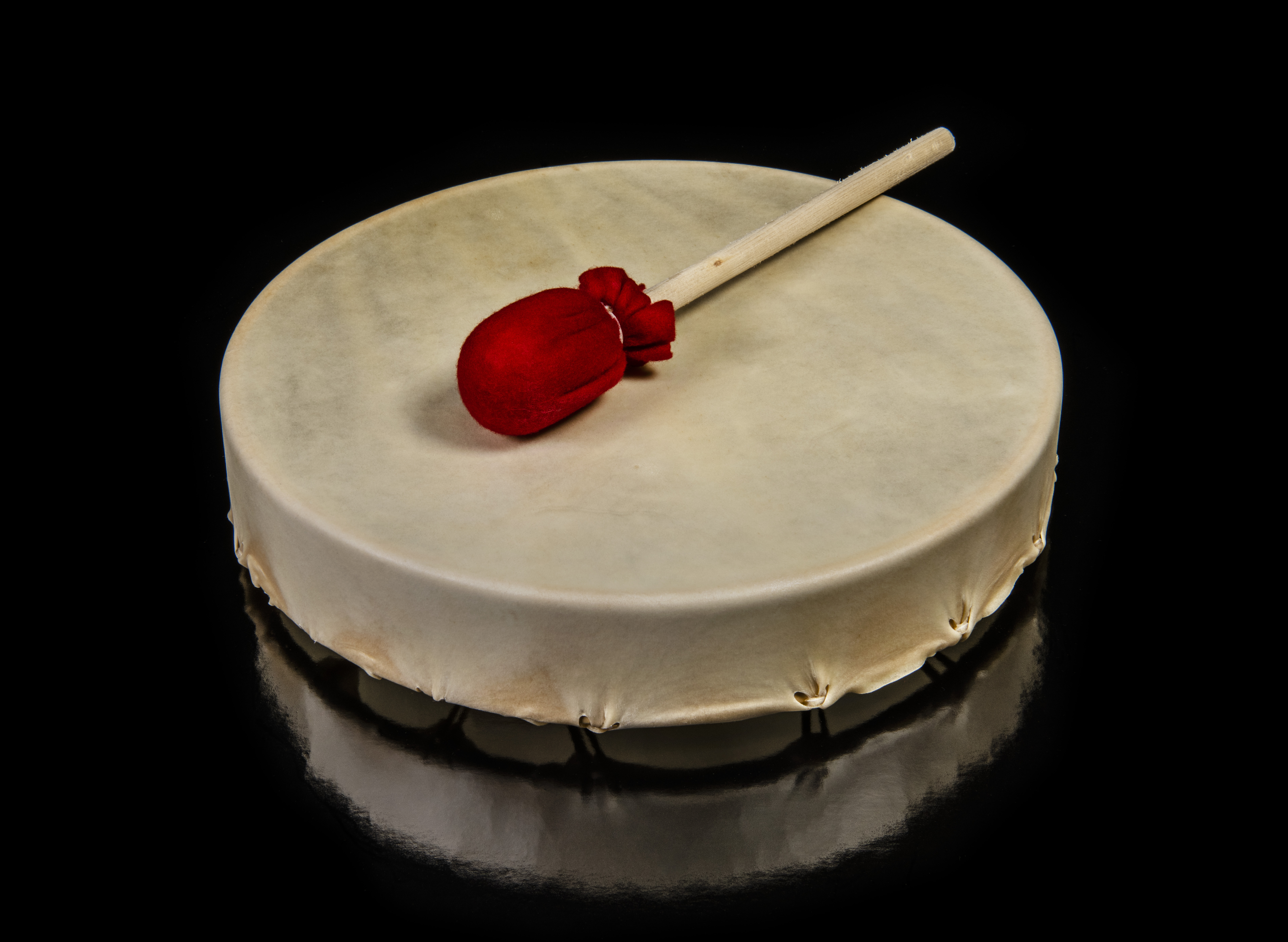 Tambour en peau avec batteur recouvert de rouge. //Skin drum with red beater