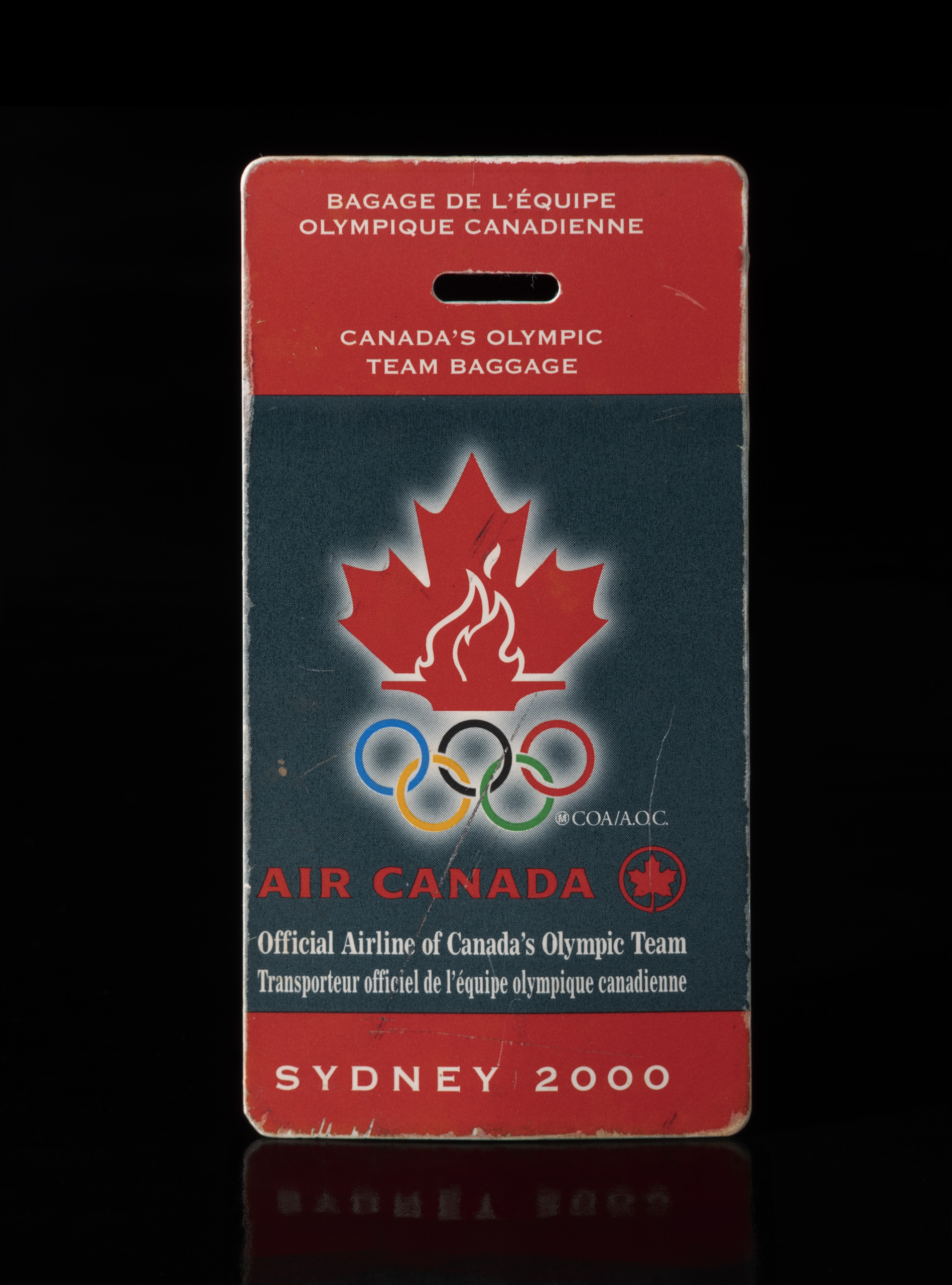 Rectangular blue and red tag with a red maple leaf and Olympic rings