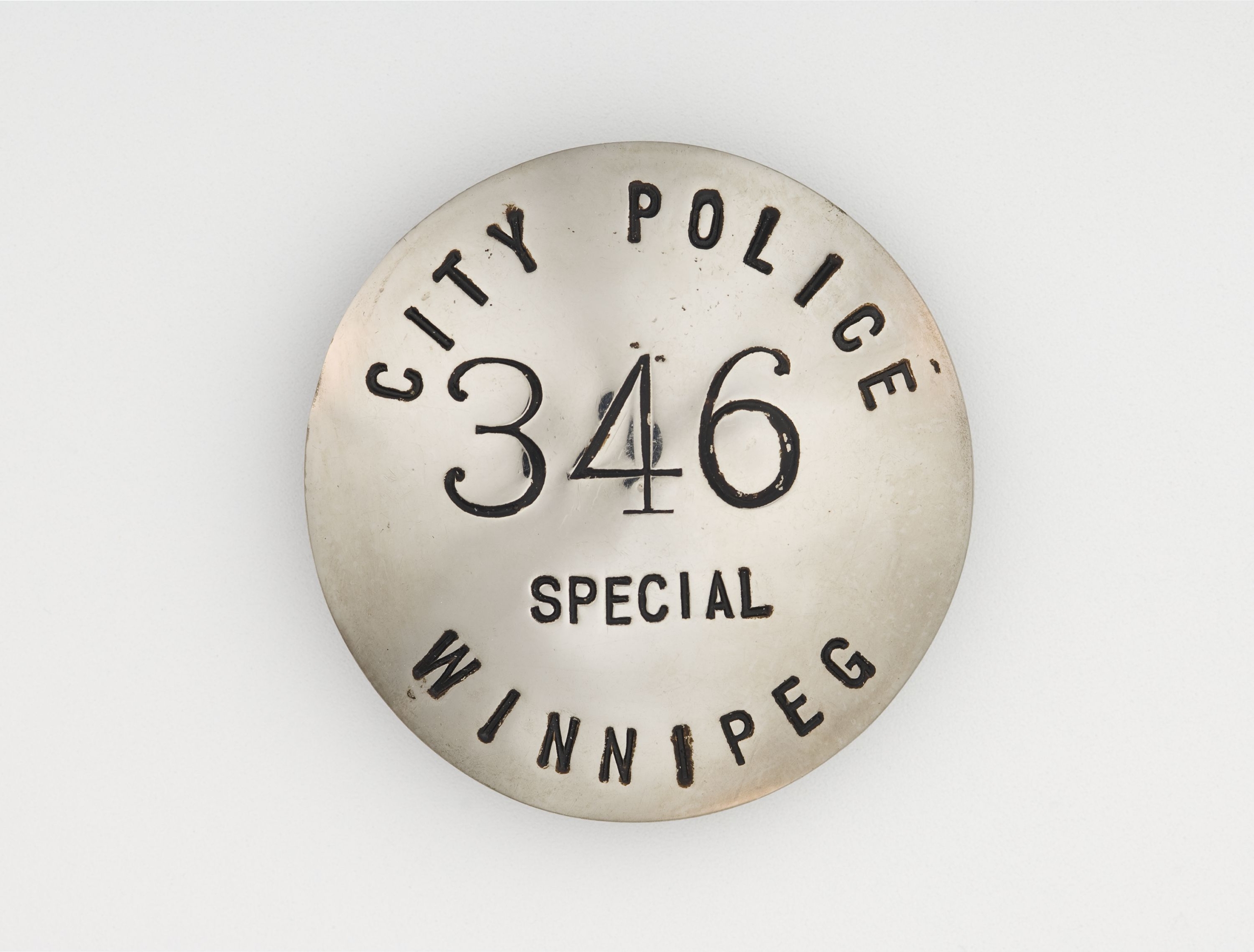 Round silver badge that reads City Police 346 Special Winnipeg