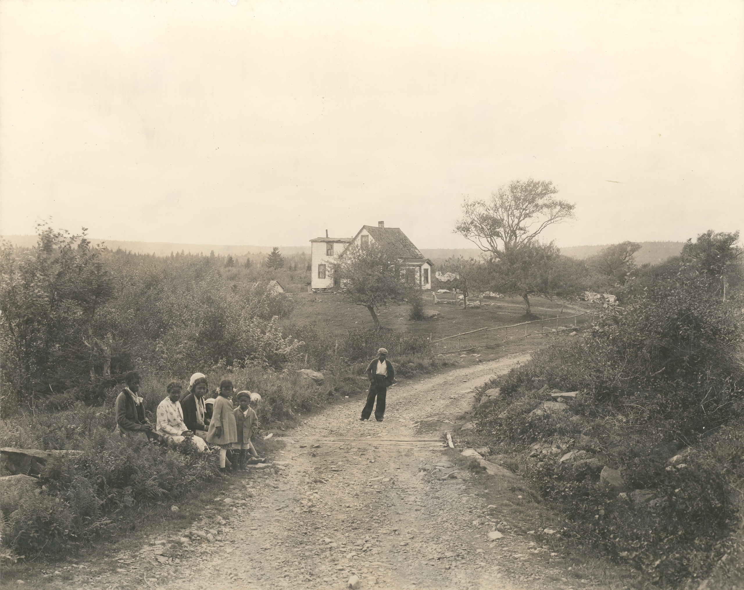 A group of children on a dirt road, with a building in the background.