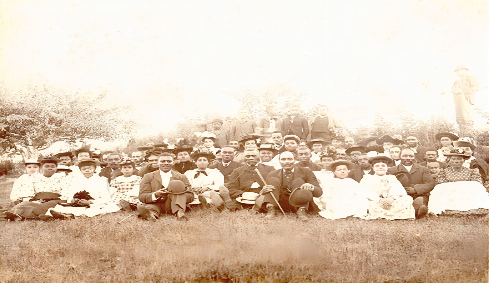 Sepia photograph showing church congregation dressed in their Sunday best. - Une photographie sépia montrant des membres d’une paroisse en habits du dimanche.