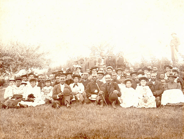 Sepia photograph showing church congregation dressed in their Sunday best. - Une photographie sépia montrant des membres d’une paroisse en habits du dimanche.